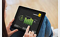 Eine Person nutzt ein Tablet, das eine App zur Energieverbrauchsanalyse anzeigt.