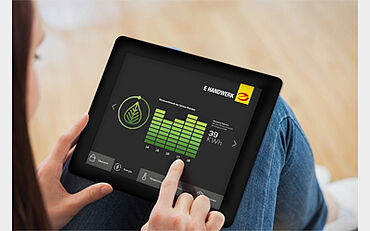 Eine Person nutzt ein Tablet, das eine App zur Energieverbrauchsanalyse anzeigt.